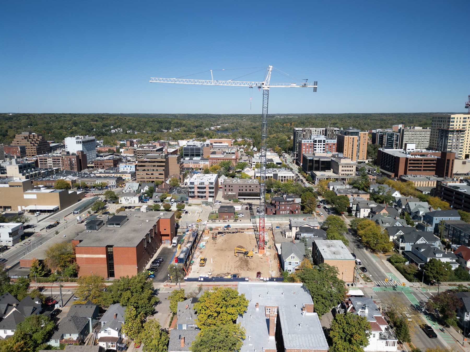 Commercial construction site, crane, and surrounding neighborhood from above