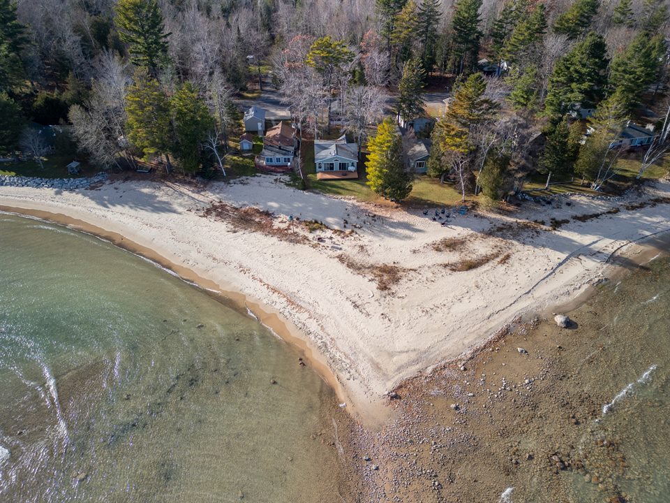 Aerial view following the shoreline past a lakefront home